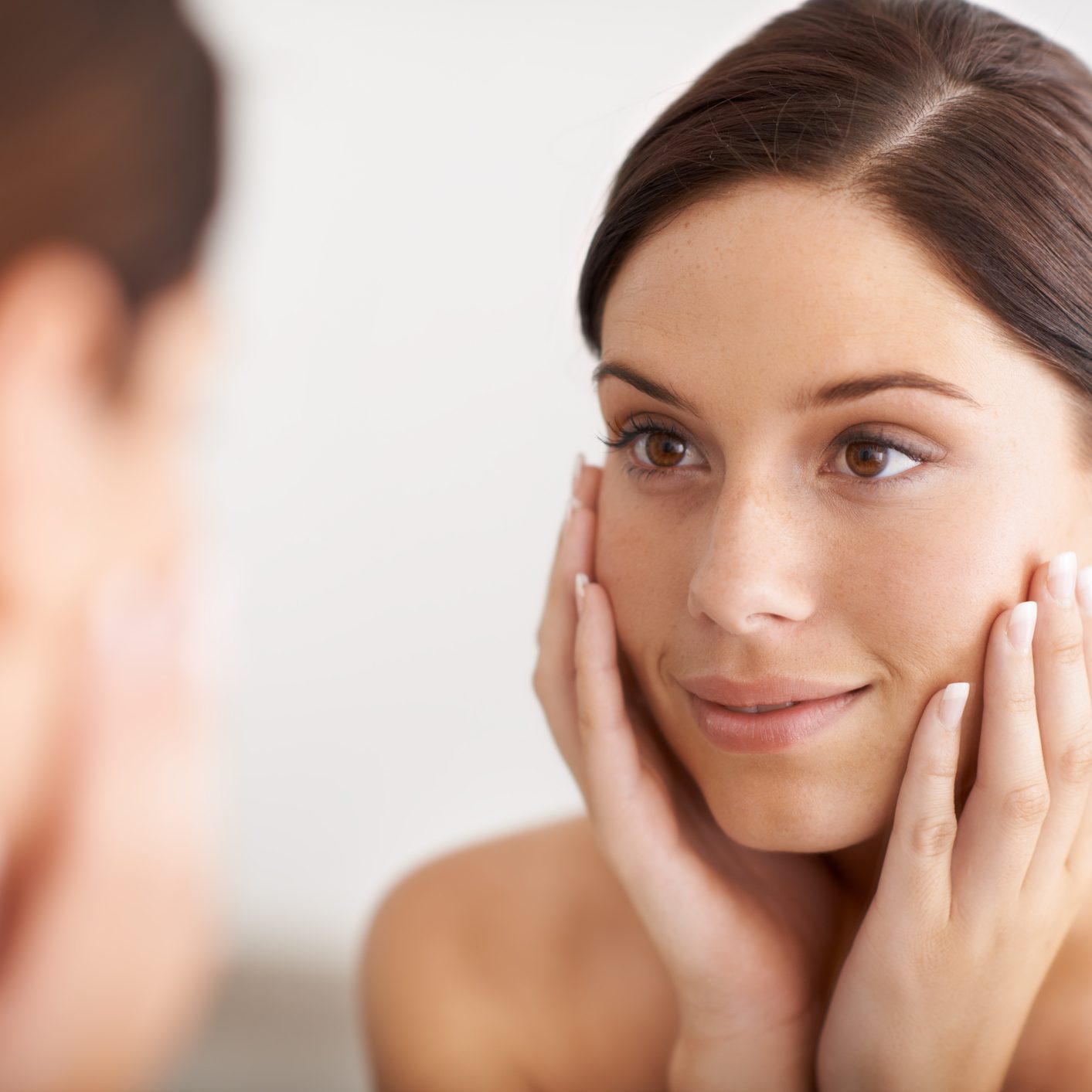 Frau schaut in den Spiegel und ist zufrieden nach der Behandlung